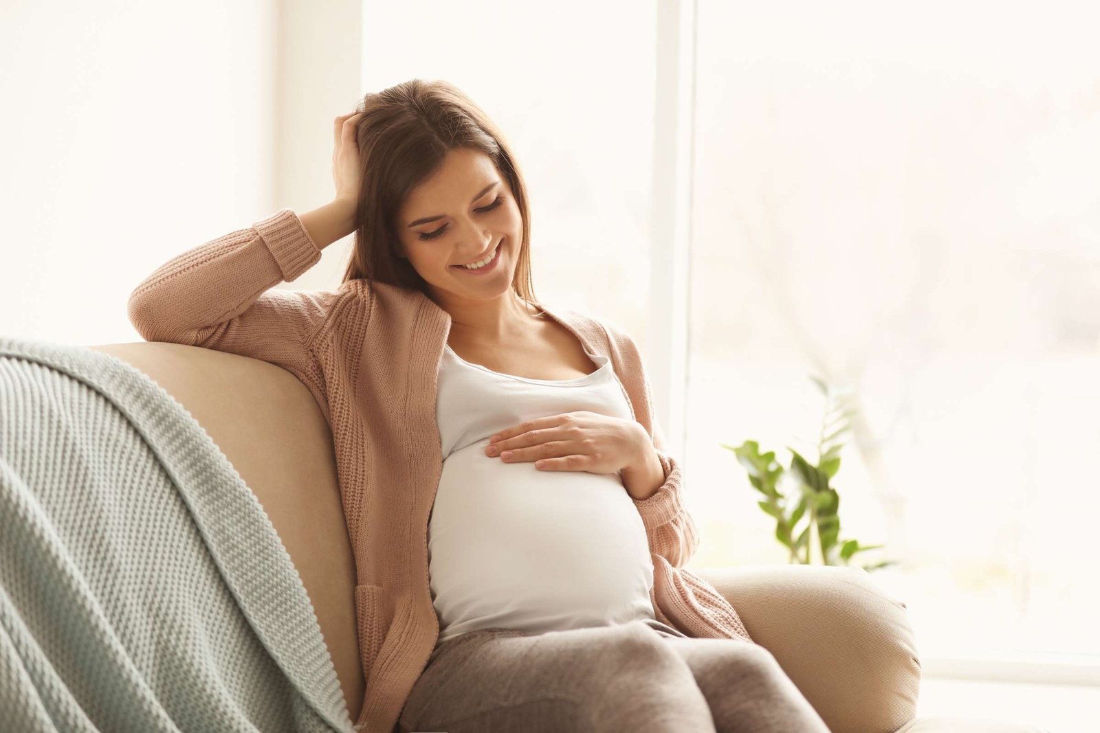 woman sitting on couch smiling at pregnant belly